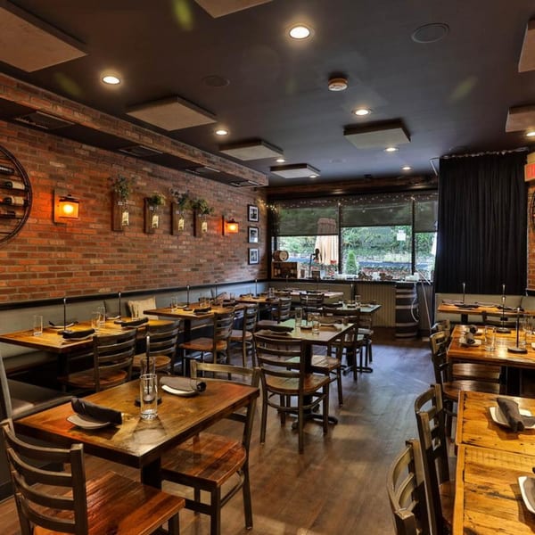 The Brick Oven Pizza dining room with rustic brick walls, wooden tables, and chairs, set for guests.