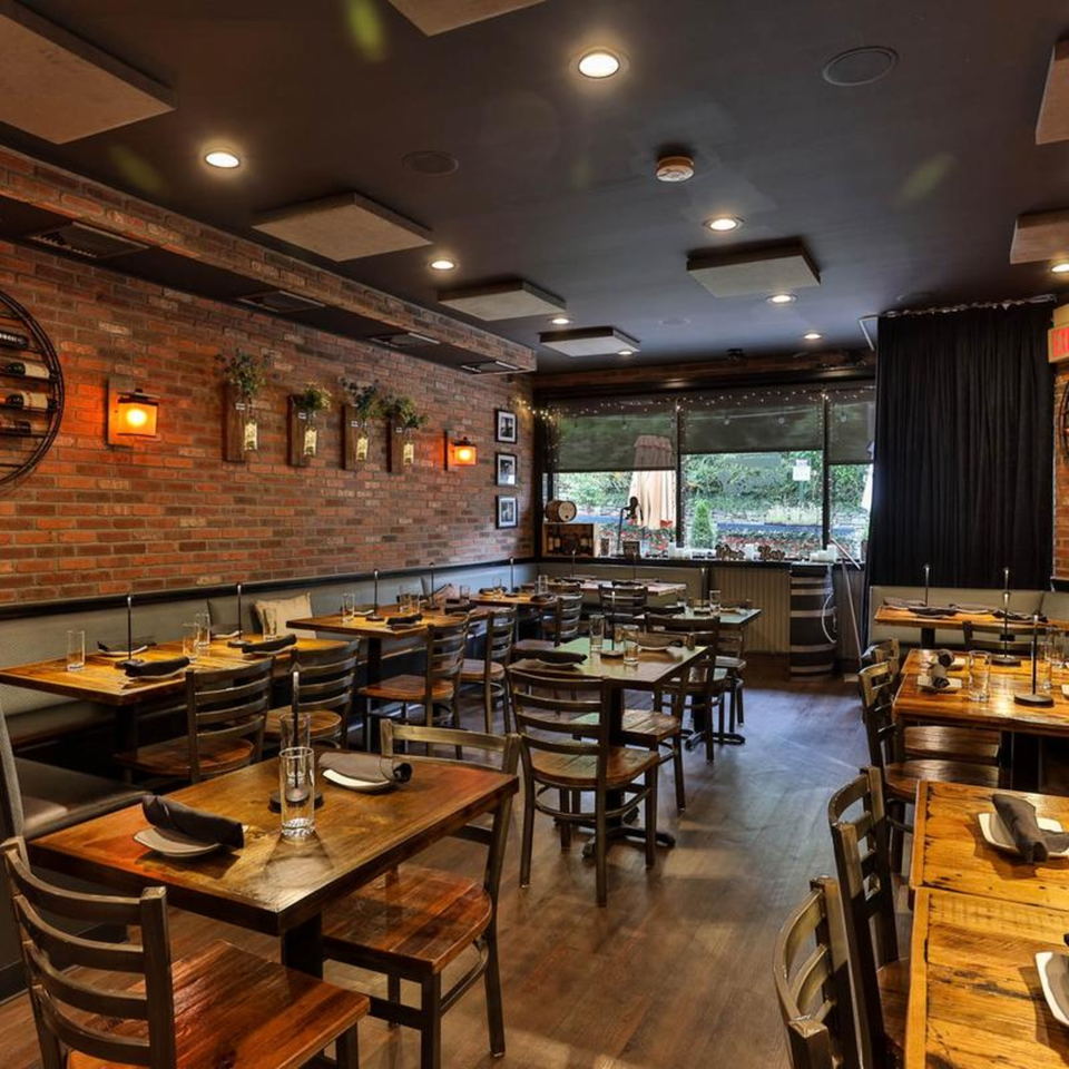 The Brick Oven Pizza dining room with rustic brick walls, wooden tables, and chairs, set for guests.