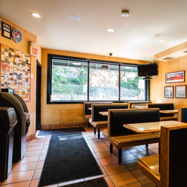 Interior of The Brick Oven Pizza dining area with booths, tiled floor, and large windows.