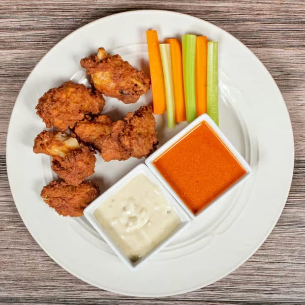 Crispy fried chicken wings with carrot and celery sticks, served with two dipping sauces.