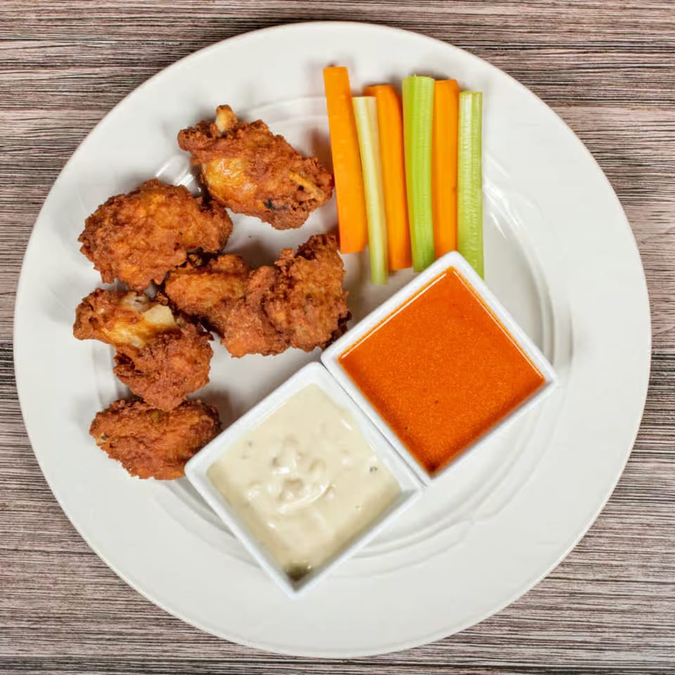 Crispy fried chicken wings with carrot and celery sticks, served with two dipping sauces.